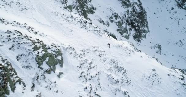 Aeriană laterală deasupra muntelui înzăpezit de iarnă, cu schiori alpiniști care se plimbă pe alpinism. Zăpadă acoperită de munți de sus și ghețar de gheață.Iarnă natură sălbatică în aer liber.4k zbor cu drone — Videoclip de stoc