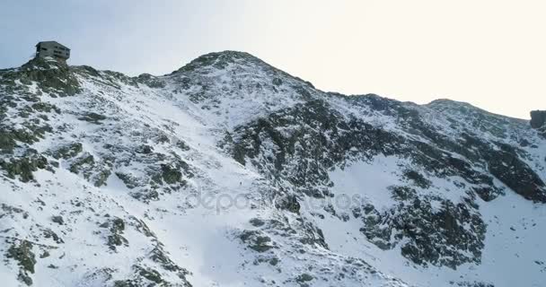 Bakåt Flygfoto över snöiga Vinterberg med bergsklättring skidåkare människor gå upp climbing.snow täckte bergen topp is glaciär. Vinter vilda naturen utomhus establisher.4k drone flyg — Stockvideo