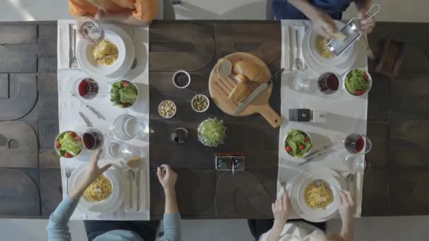 Napowietrznych góry tabeli czterech kaukaski przyjaciół jeść Makarony włoskie spaghetti carbonara lunchem lub kolacją, picia, opiekania wraz z kieliszki do czerwonego wina. Letnia impreza w domu w nowoczesnym domu wideo — Wideo stockowe