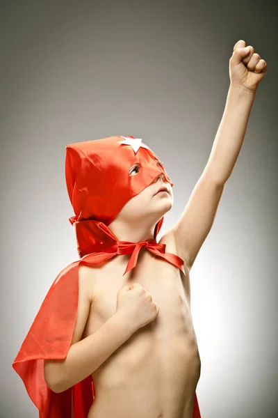 Joven niño superhéroe volar con capa y máscara retrato sobre fondo gris —  Fotos de Stock