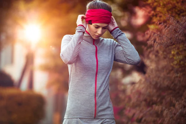 Fiatal gyönyörű nő előkészítése képzés edzés. Őszi futás fitness lány őszi fák orange city városi park környezetben. Naplemente vagy napfelkelte meleg fény. A hideg évszak sport tevékenység — Stock Fotó