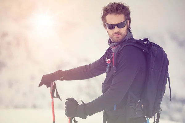 Skier man detail with sunglasses. exploring snowy land walking and skiing with alpine ski. Europe Alps. Winter sunny day, snow, wide shot, warm sun flare.travelling — Stock Photo, Image