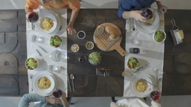 Rezsi felülnézet táblázat négy kaukázusi meg eszik carbonara olasz spagetti tészta, az ebéd és a vacsora, ivás, pirítás együtt vörös bor, poharak. Nyáron fél otthon, modern ház videó — Stock videók