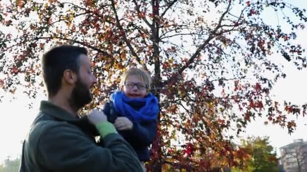 Père jouant et tenant son fils au parc urbain de la ville. Joyeux papa un garçon enfant embrassant une journée d'automne en plein air ensemble. Coucher de soleil, rétroéclairage. Ensemble, la famille et l'enfance concept.4k vidéo portable tourné — Video