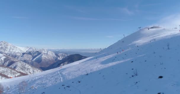 Seitliche Antenne folgen Menschen Skifahrer Ski Alpin im Winter schneebedeckten Berg Skipiste Feld in sonnigem Tag.italy Alpen Berge Schnee Saison aktiver Skisport.4k Drohnenflug — Stockvideo