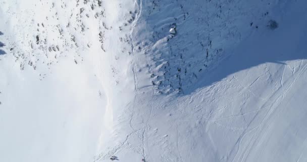 Ovanför översta Flygfoto över vintern snowy mountain ski friidrott med människor i solig dag. Ovanför Alperna snö berg säsong establisher.4k drone flygning att upprätta skott rakt ner perspektiv — Stockvideo