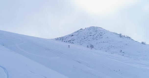 Side aerial over winter snowy mountain ski track field with mountaineering skier people walking up climbing.Snow covered mountains.Fog clouds rising.Winter nature outdoor sport establisher.4k drone — Stock Video