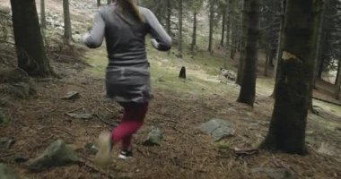 Kadın soğuk mevsimde ormanda koşuyor. Açık havada kötü hava koşan bir sporcu. Ormanda kış koşusu. Geriye bakış. Sportif kadın koşuyor..