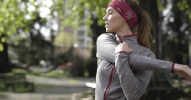 Kvinna värma upp stretching för löpning träning.woman kör aktiv längs stadens gata och parkera i kall säsong. Dålig väderlöpare. Vintern kör i urban park.Back view.sportig kvinna kör. — Stockvideo