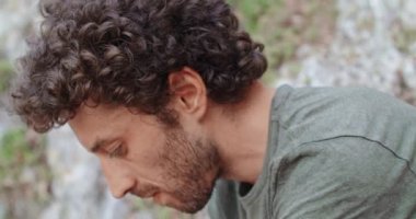 Dağcı adam ayakkabı koyarak kayalık duvar yarığına tırmanmaya hazırlanıyor. Aşırı aktif spor aktivitesi tırmanma. Aktif insanlar, açık hava etkinlikleri. Yüz yüze. Yavaş çekim 4k video.