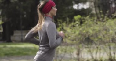 Kadın soğuk mevsimde şehir caddesinde koşuyor ve park ediyor. Kötü hava koşucusu. Şehir parkında kış koşusu. Geriye bakış. Sportif kadın koşuyor..