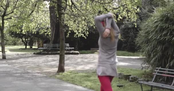 Kvinna värma upp stretching för löpning träning.woman kör aktiv längs stadens gata och parkera i kall säsong. Dålig väderlöpare. Vintern kör i urban park.Back view.sportig kvinna kör. — Stockvideo