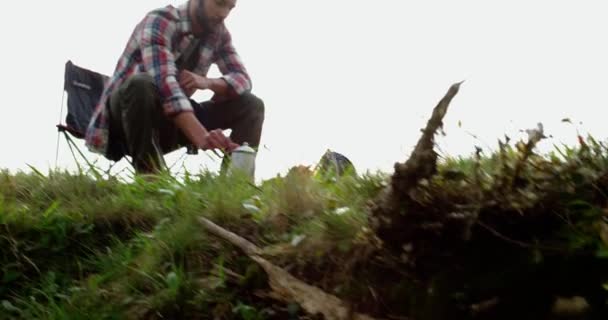 Aventura hipster hombre cocina desayuno o almuerzo cerca de la tienda de campaña hi. mochilero acampando en zona rural. Muy cerca. Hombre camping viaje.Hombre preparando fogata . — Vídeos de Stock