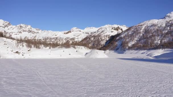 Aéreo sobre el lago helado cubierto de nieve en el valle de la montaña en el soleado día de invierno.Europa Alpes montañas al aire libre establishment. — Vídeo de stock