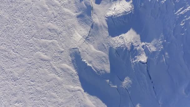 Ovanifrån över glaciären täckt av snöwirh klyftor och revor. Vinterland utomhus etablerare.4k drönare overhead framåt flygning etablerar skott. Skuggor över snö på solig dag — Stockvideo