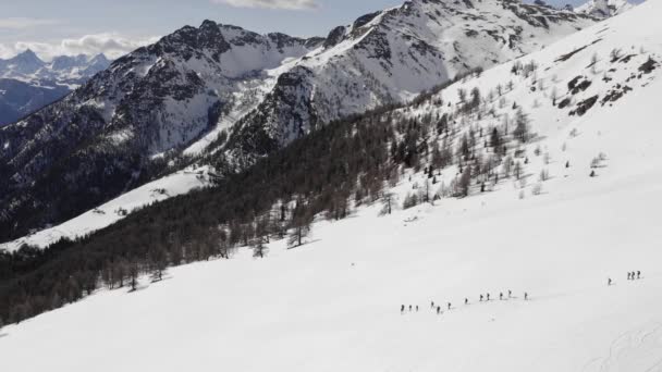 Vinter antenn över grupp människor med snöskor vandrar ner för en snöig sluttning. Vinter Wonderland panorama med aktiva människor.Berg utomhus etablerare.4k drone cirkel pan flygning — Stockvideo