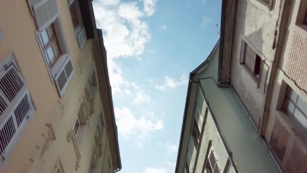 Widok z dołu na tradycyjne domy we Freiburgu, Niemcy. Spacerując wzdłuż małej ulicy starego miasta patrząc w górę dachów. Tradycyjne dachy niemieckich domów. Słoneczny dzień. — Wideo stockowe