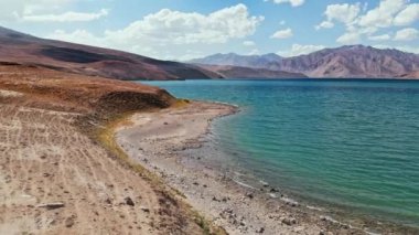 Güneşli bir günde Bulunkul Gölü kıyısındaki havadan. Tacikistan çölünde Pamir karayolu ipeği yolculuğu macerası. Orta Asya bölgesi. 4k İHA uçuş kurulum videosu