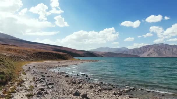 Aérea sobre la orilla del lago Bulunkul en un día soleado.Pamir carretera ruta de la seda aventura de viaje en Tayikistán árido desierto, Asia central.Región de Khorugh. 4k drone vuelo Establecimiento de vídeo — Vídeo de stock