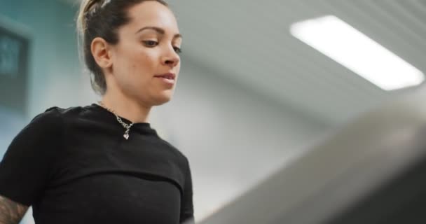 Jeune femme courant sur un tapis roulant au gymnase. Vue de face rapprochée, détail du haut du corps. Entraînement de femme au centre de fitness. Femme faisant de l'exercice cardio 