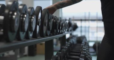 Spor salonunda halter kaldıran bir kadın. Ağırlık kaldırmanın ayrıntıları. Spor salonunda kadın eğitimi. Fitness kız dayanıklılık egzersizi kapalı alanda.