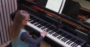 Çocuk evde piyano çalmayı öğreniyor. Çocuk piyano çalışıyor. Küçük kız piyano çalıyor.