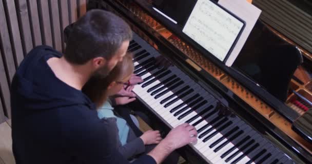 Ο μπαμπάς διδάσκει πιάνο στην κόρη του.Κοριτσάκι μαθαίνει πιάνο στο σπίτι.Κάτοψη. Παιδί μαθαίνει πιάνο από τον πατέρα της — Αρχείο Βίντεο