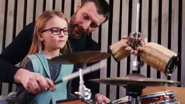 Père et fille jouent ensemble des percussions. Petite fille apprenant la batterie avec son père à la maison. Vue de face. Cours de percussions à la maison. — Video