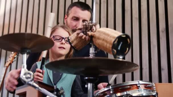Отец и дочь играют вместе на ударных. Девочка учится играть на барабанах с отцом дома. — стоковое видео