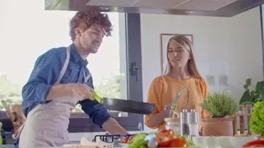İki kişi evde yemek pişiriyor ve yemek hazırlıyor. Genç çift evde yemek pişiriyor. Erkek ve kadın mutfakta yemek pişiriyor. Sağlıklı yemek, sebze, domates, salata. Ön görünüm MS