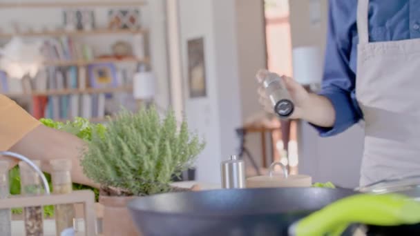 Twee mensen thuis koken en koken. Jong stel kookt thuis en bereidt lunch voor. Man en vrouw koken in keuken.Gezond eten, groenten, tomaten, salade. Zijaanzicht van dichtbij — Stockvideo