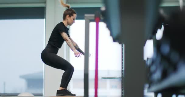 Vrouw springt op box in de gym.Woman benen training. Vooraanzicht MS, slow motion. Fitness cardioactiviteit. Vrouwentraining in de sportschool — Stockvideo