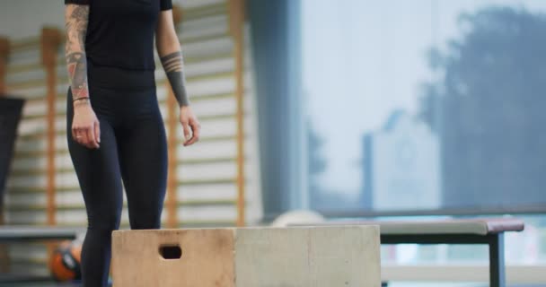 Mulher pulando na caixa no ginásio. Mulher pernas formação. Visão frontal MS, câmara lenta. Atividade cardio fitness. Mulher treinando no ginásio — Vídeo de Stock