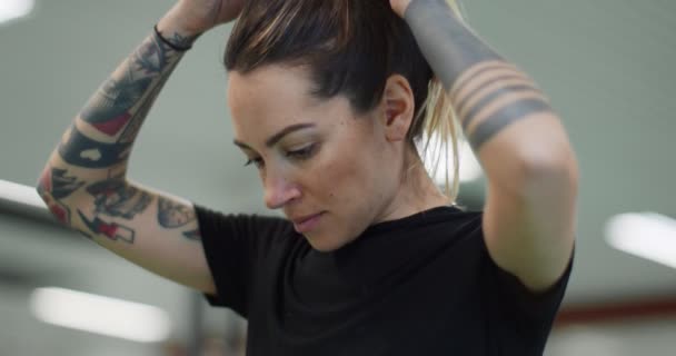 Mulher descansando durante o treino no ginásio.Mulher cansada relaxando durante o intervalo de fitness. Vista frontal, de perto. Mulher aquecendo alongamento — Vídeo de Stock