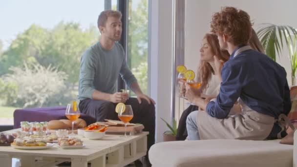 Чотири друзі щасливі розмовляють, їдять і п'ють коктейль. Щаслива група людей насолоджується сучасною домашньою вечіркою або обідом. — стокове відео