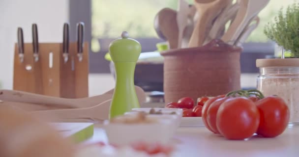 Detalle de la mesa de la cocina con tomates y herramientas. Cucharas, cuchillos y comida en la mesa de la cocina. Dieta saludable verduras, ensalada. Casa moderna — Vídeo de stock