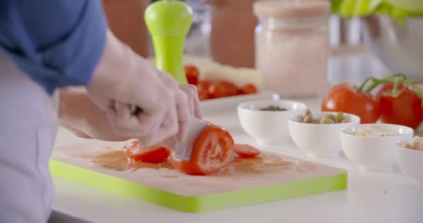 Detail of mans hand cutting tomatoes at home open space kitchen. Mediterranean healthy diet vegetables,tomatoes,salad. Modern love relationship,helping.4k video — Stock Video