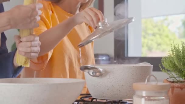 Hombre mezcla de pasta de espaguetis en pote de agua hirviendo. Dos personas pareja preparando almuerzo italiano en casa moderna cocina de espacio abierto . — Vídeos de Stock