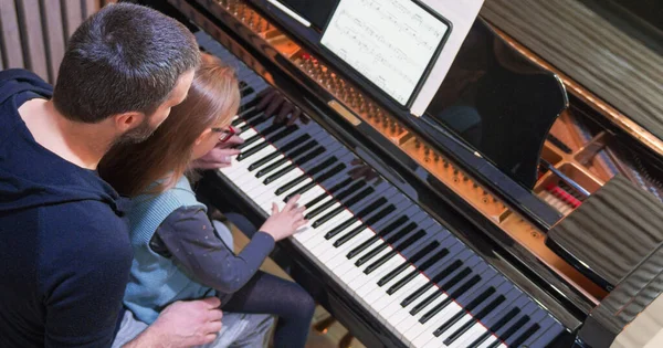 Papà insegna pianoforte alla figlia.Bambina che impara il pianoforte a casa.Vista superiore.Lezione di pianoforte a casa. Bambino che impara il pianoforte da suo padre — Foto Stock