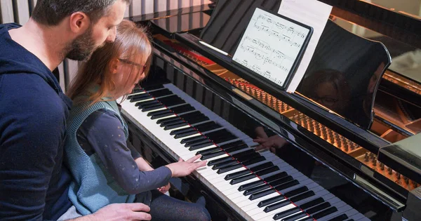 Dad teaching piano to his daughter.Little girl learning piano at home.Top view.Piano class at home. Child learning piano from her father