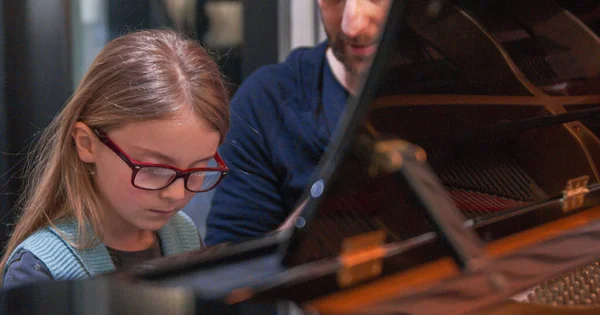 Aula de piano com professor e aluno aprendendo. Kid aprendendo a tocar piano com professores.Menina aprendendo aula de piano. Vista lateral.Aula de piano em casa. Criança aprendendo piano com seu professor — Fotografia de Stock