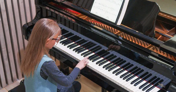 Ungen lär sig att spela piano hemma.Ungen övar piano.Sidovy.Liten flicka spelar piano — Stockfoto