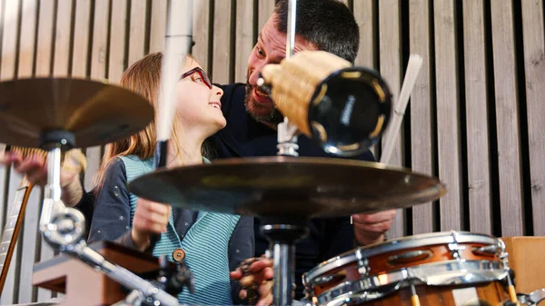 Padre e figlia godono di suonare musica insieme.Bambina sorridente imparare la batteria con il padre a casa.Vista anteriore.Classe di percussione a casa — Foto Stock