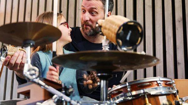 Padre e figlia godono di suonare musica insieme.Bambina sorridente imparare la batteria con il padre a casa.Vista anteriore.Classe di percussione a casa — Foto Stock