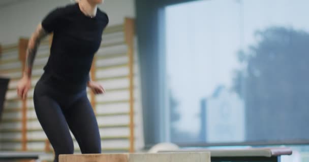 Mujer saltando en la caja en el gimnasio. Entrenamiento piernas de mujer. Vista frontal MS, cámara lenta. Actividad cardiovascular fitness. Entrenamiento de mujer en gimnasio — Vídeo de stock