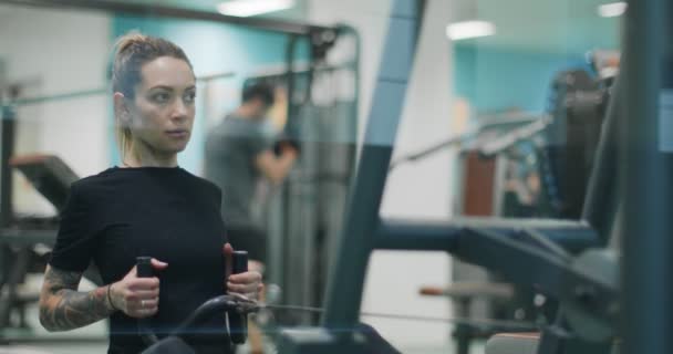 Mujer haciendo ejercicio con máquina de remo en el gimnasio.Vista frontal, cámara lenta. Entrenamiento de la mujer en el remo — Vídeos de Stock