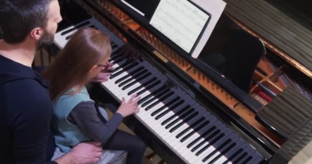 Apa zongorát tanít a lányának.Kislány zongorázni tanul.Top view.Piano osztály otthon. A gyermek zongorázni tanul az apjától. — Stock videók