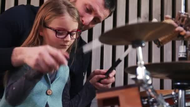 Padre e hija tocan la percusión juntos. Niña aprendiendo batería con su padre en casa. Vista frontal. Clase de percusión en casa. — Vídeos de Stock