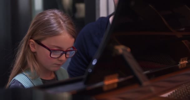 Clase de piano con profesor y niño aprendiendo.Niño aprendiendo a tocar el piano del profesor.Niña aprendiendo lecciones de piano.Vista lateral.Clase de piano en casa. Niño aprendiendo piano de su maestro — Vídeo de stock