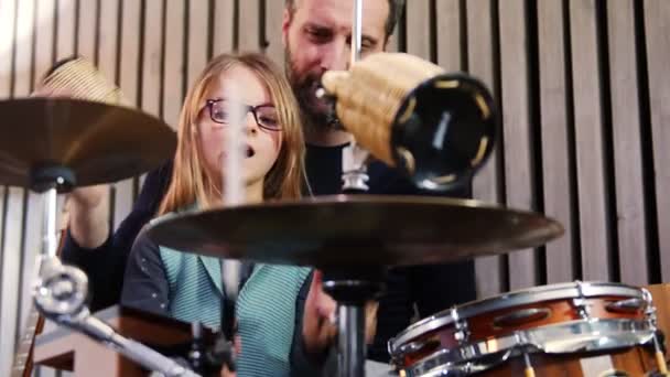 Pai e filha tocam percussão juntos.Pequena menina aprendendo bateria com seu pai em casa.Vista frontal.Aula de percussão em casa — Vídeo de Stock